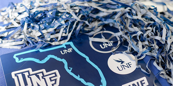 UNF stickers and blue and gold tassel on a laptop